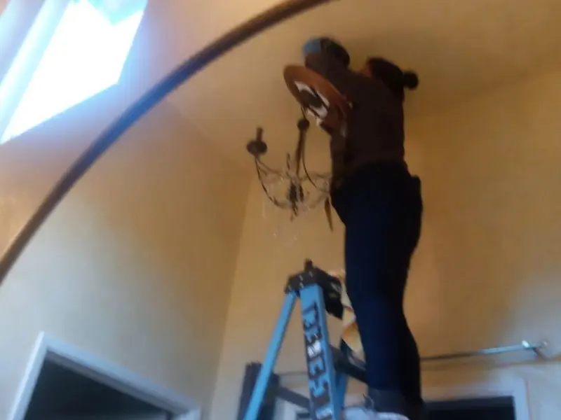 Electrician installing a chandelier in a St. Charles residence